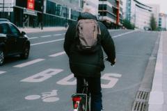 Een fietser met een regenjas en een rugzak aan is op weg naar zijn werk. 