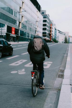 Een fietser met een regenjas en een rugzak aan is op weg naar zijn werk. 